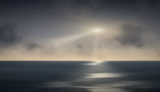 Light breaking through storm clouds over the sea, a picture of trusting God in hard times